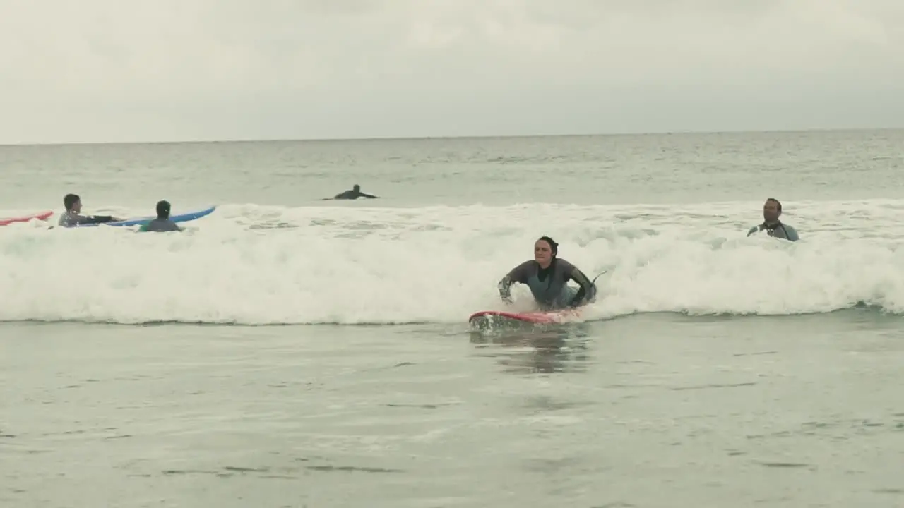 Young female surfing on cloudy day in Portugal Algarve on small wave in Atlantic Ocean