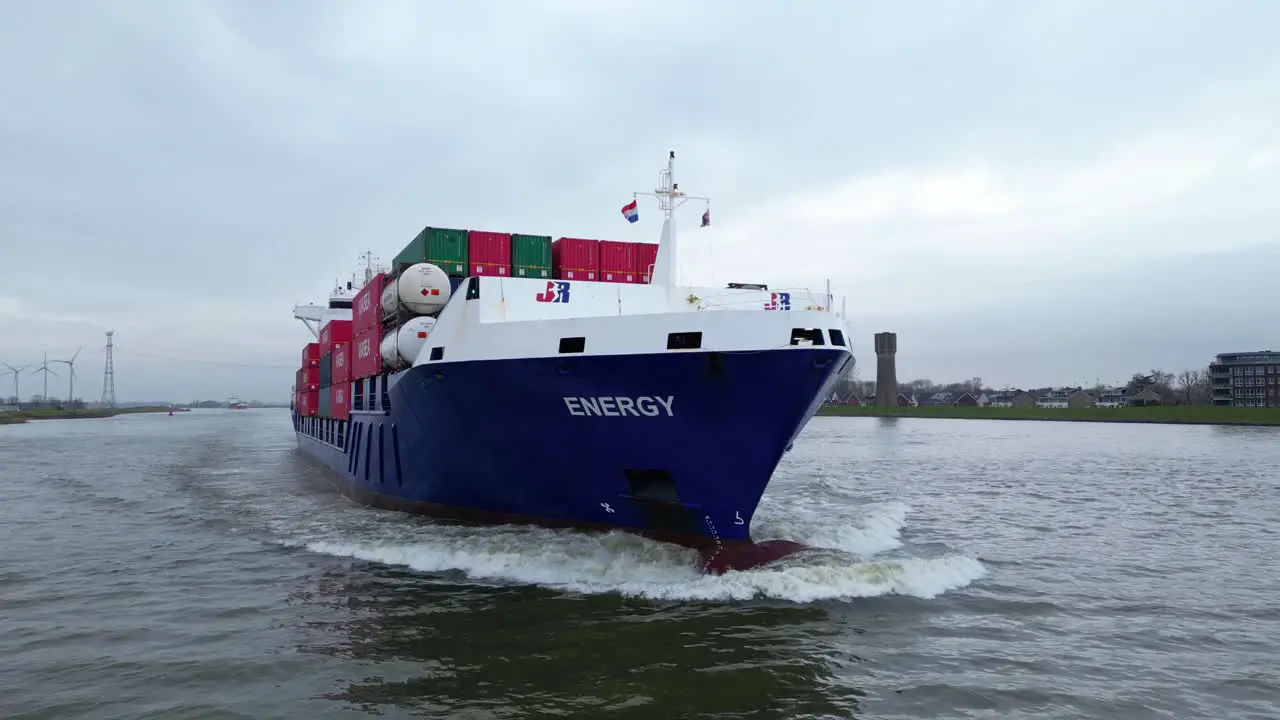 Aerial Flying Close Around Forward Bow Of Energy Cargo Ship Carrying Viasea Intermodal Containers Passing Along Oude Maas