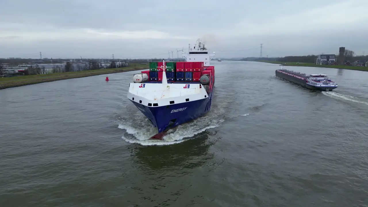 Aerial Parallax Shot Around Forward Bow Of Energy Cargo Ship Carrying Viasea Intermodal Containers Passing Along Oude Maas