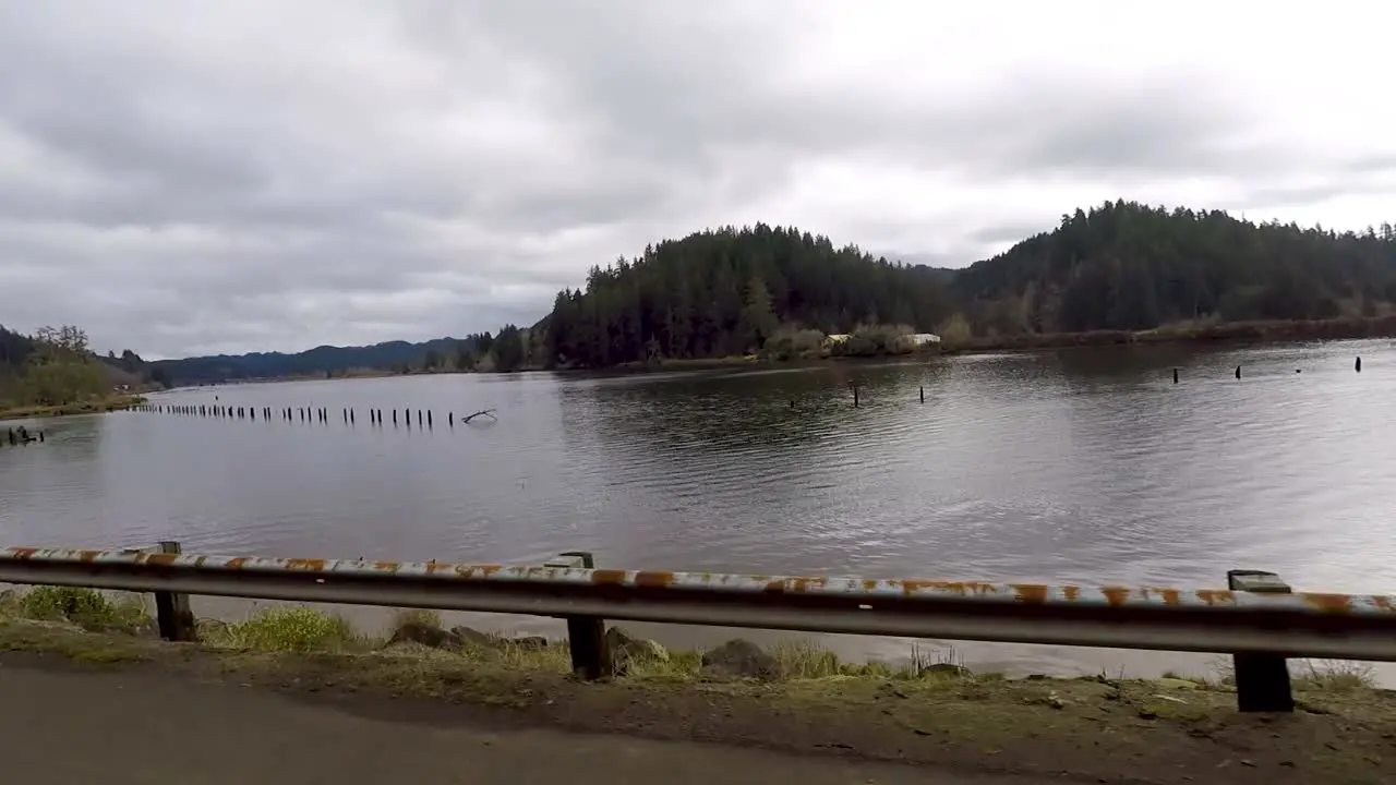 Driving by a river with pilings sticking out of the water that where used for logging floating logs down the river and tie them up