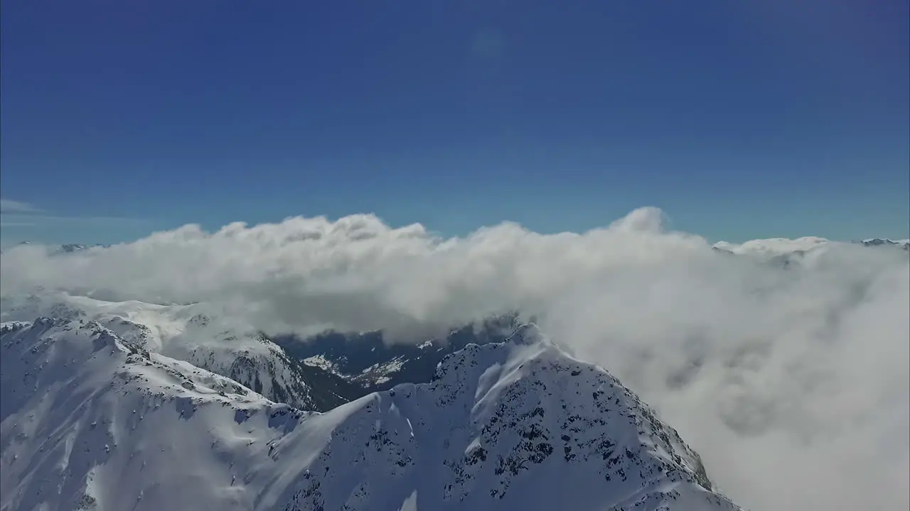 Aerial over clouds and snowy mountain peak during winter in Latvia