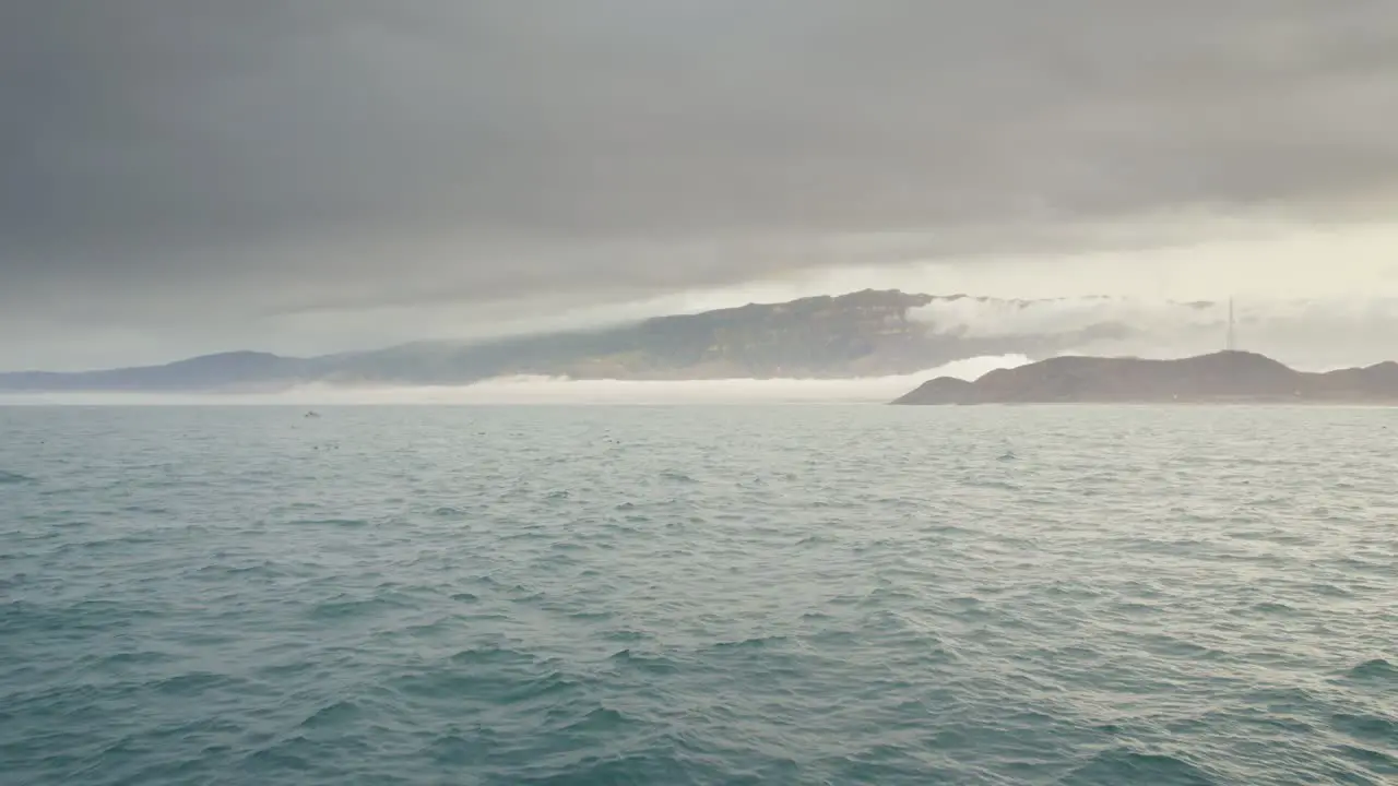 cinematic shot of man standing on rocks in the sea