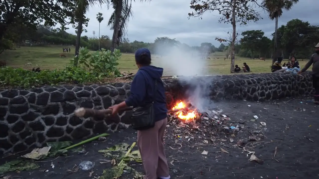 Balinese Women Burns Plastic Trash Making Fire at the Beach Pollution and Smoke Environmental Issues in Bali Indonesia Saba Beach Gianyar