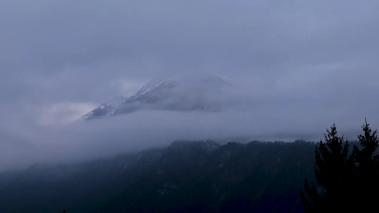 Clouds moving fast and covering up a mountain ins Switzerland