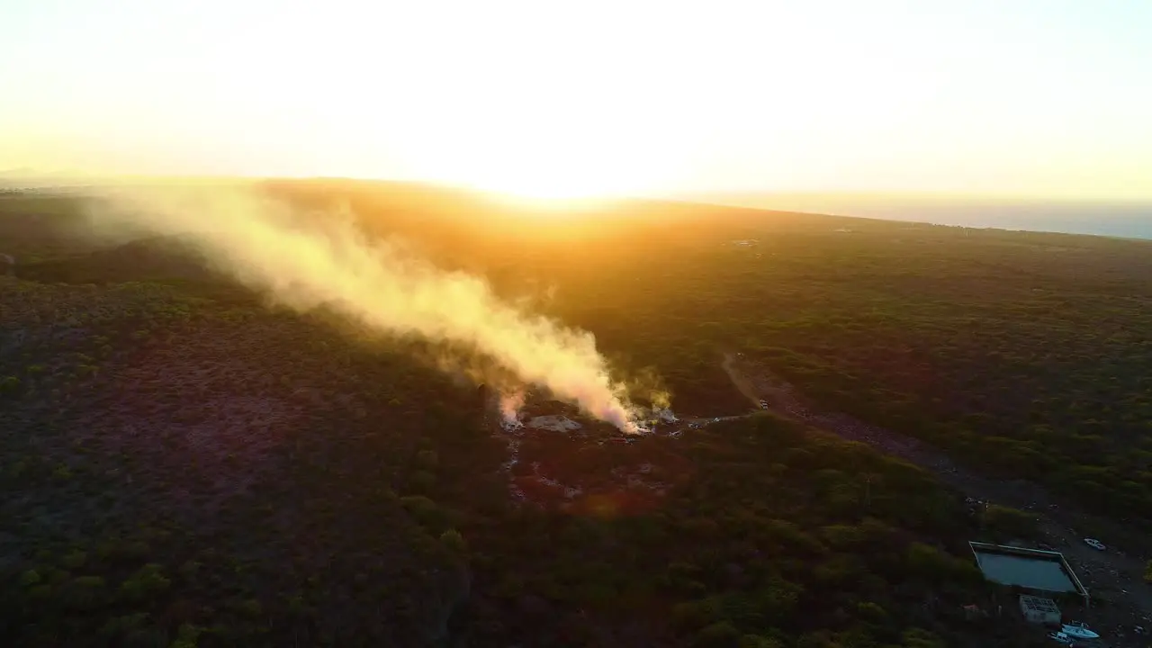 Drone rise tilt down to smoking pits on northisde curacao at sunset industrial burning