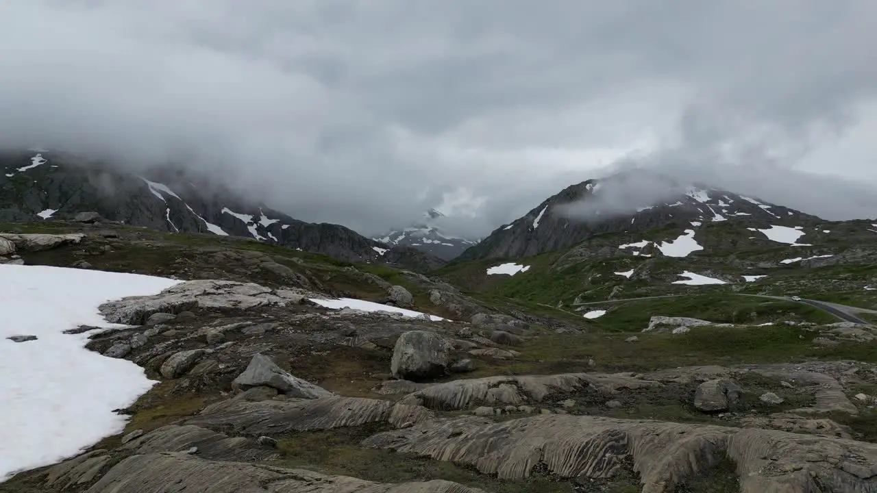 Scandanavian aerial mountain landscape with green grass rocks snow road norway