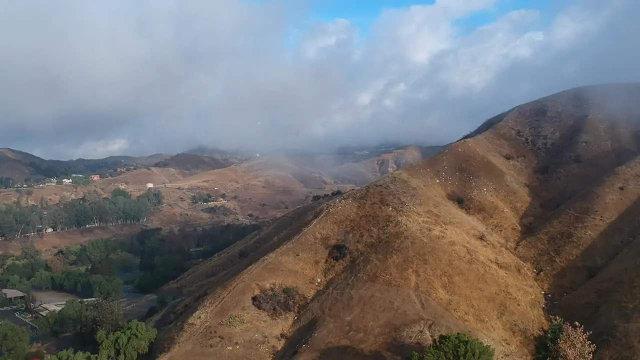 Drone footage of helicopter flying over cloudy mountains in Los Angeles California