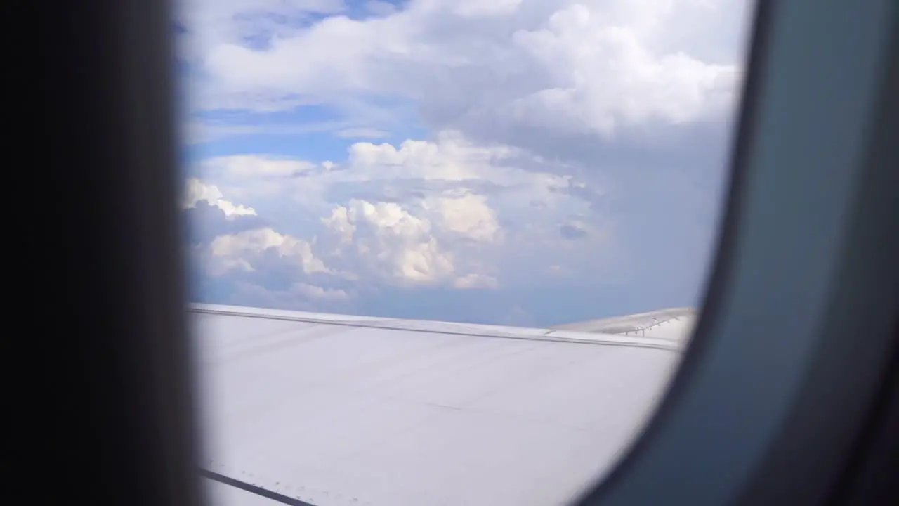 Slow motion view outside of airplane window with cloudy blue sky