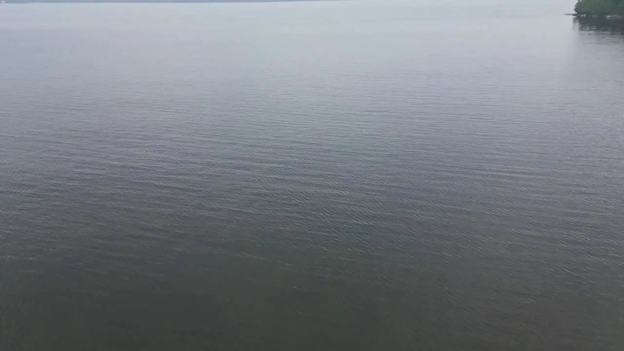 Flying Above Calm Waters Of A Lake On A Cloudy Day drone shot