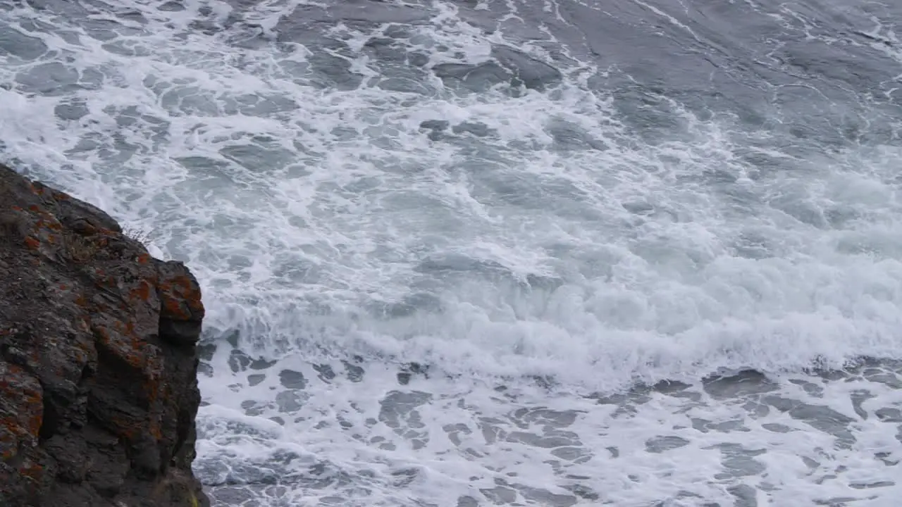 Panning from left to right going from a rock to a sea wave