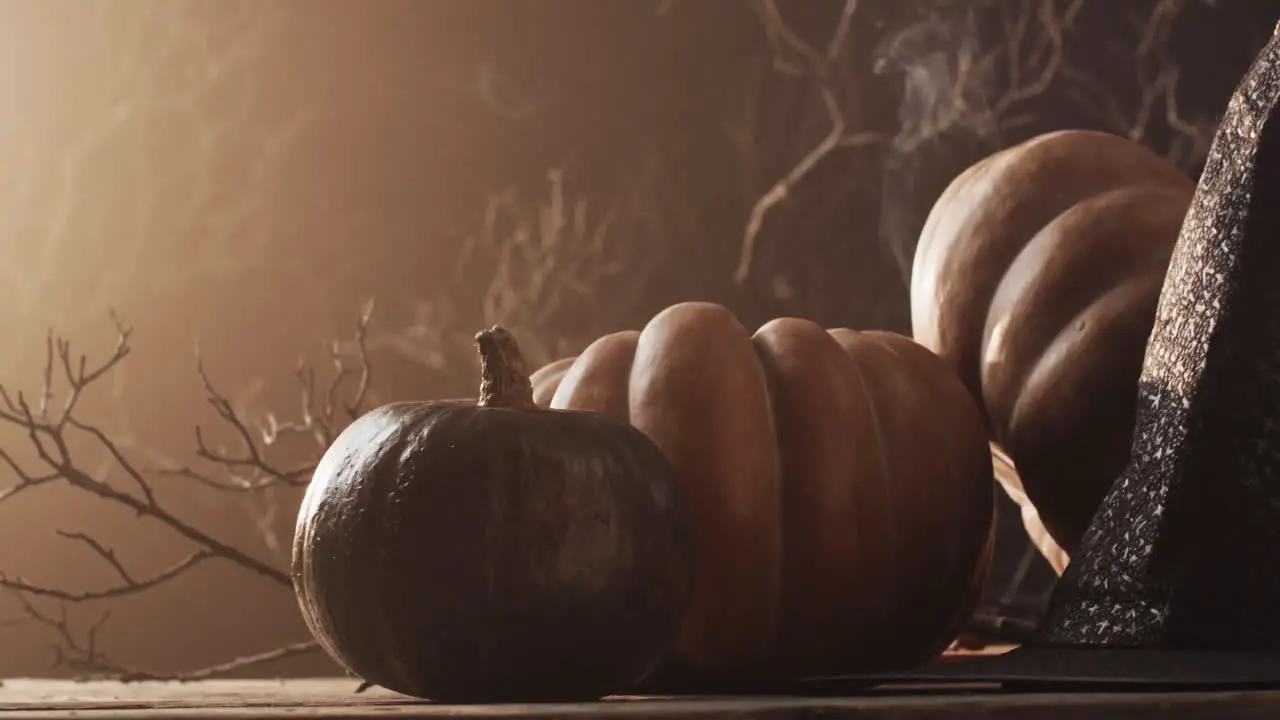 Video of halloween pumpkins hat smoke and copy space on brown background