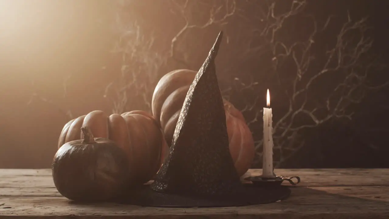 Video of halloween pumpkins hat candle and copy space on brown background