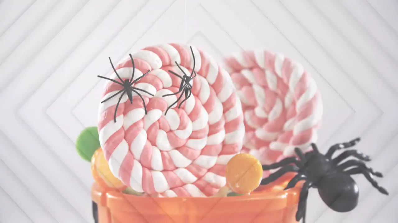 Spiders falling over in halloween pumpkin bucket filled with candies against concentric squares