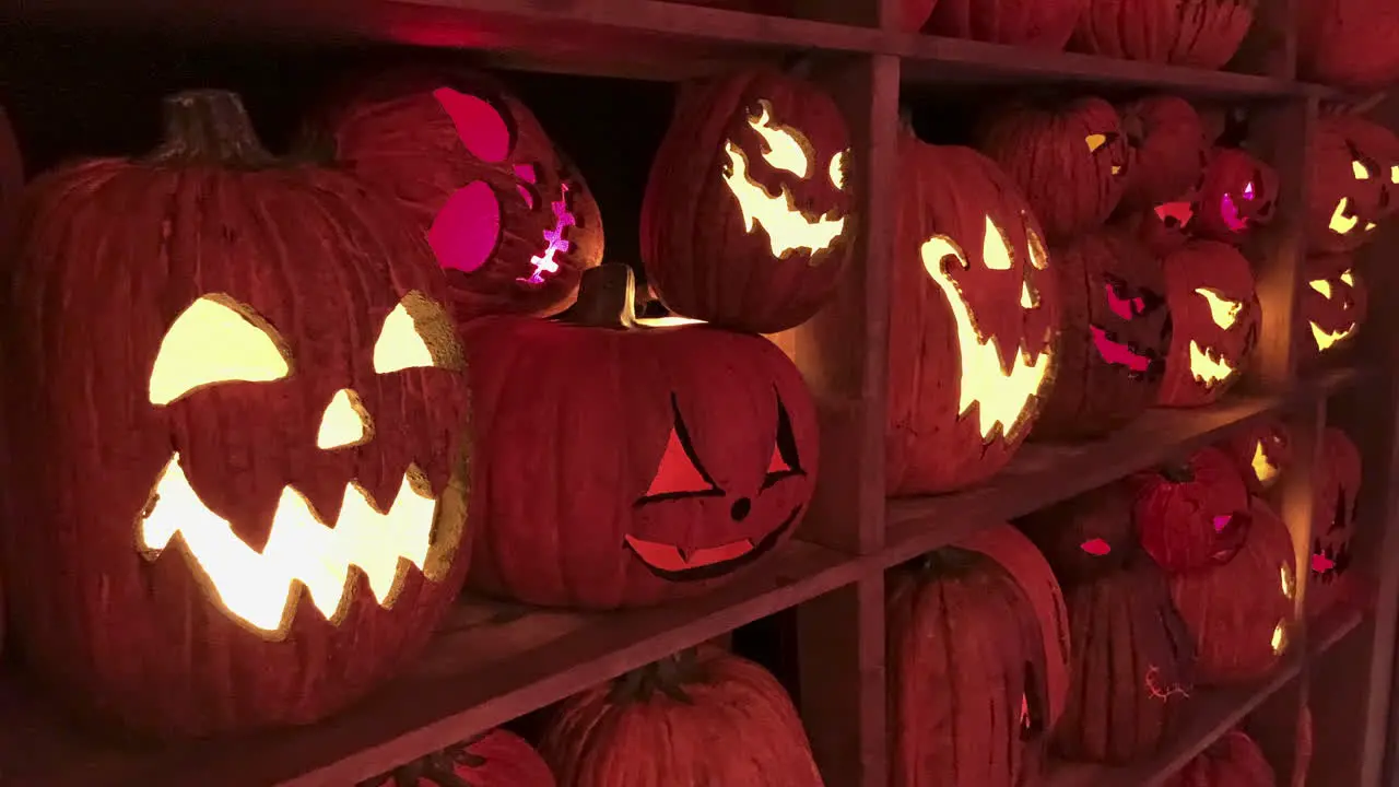 Creepy Halloween Pumpkin Heads On Shelf Board indoors lighting by candles in the dark