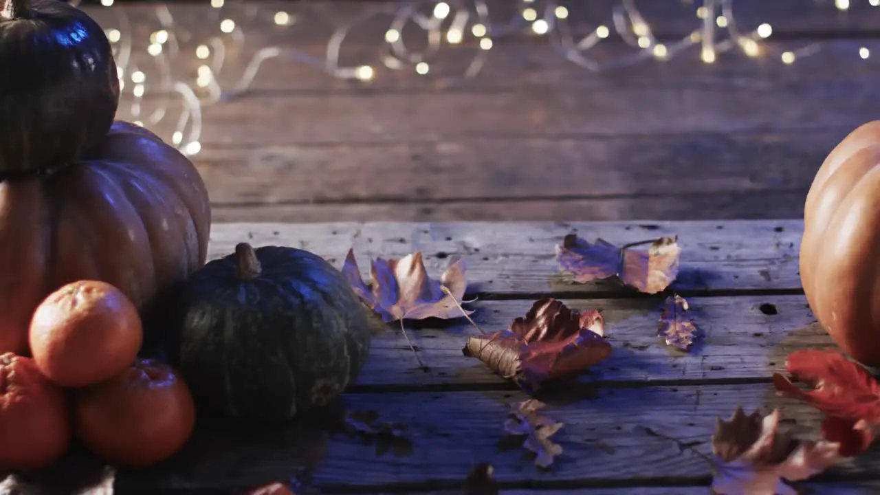 Video of halloween pumpkins with leaves and copy space on wooden background