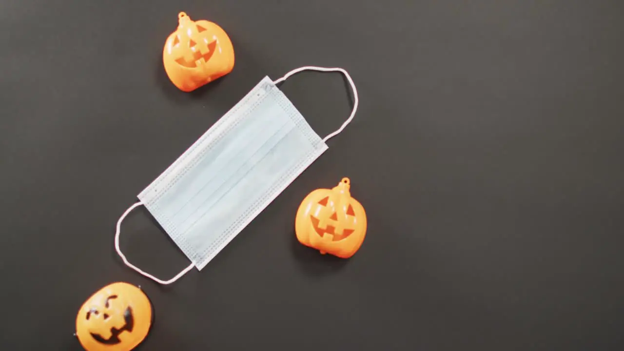 Three halloween pumpkin toys and face mask against grey background