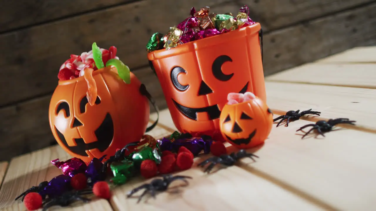 Halloween pumpkin buckets full of halloween candies on wooden surface