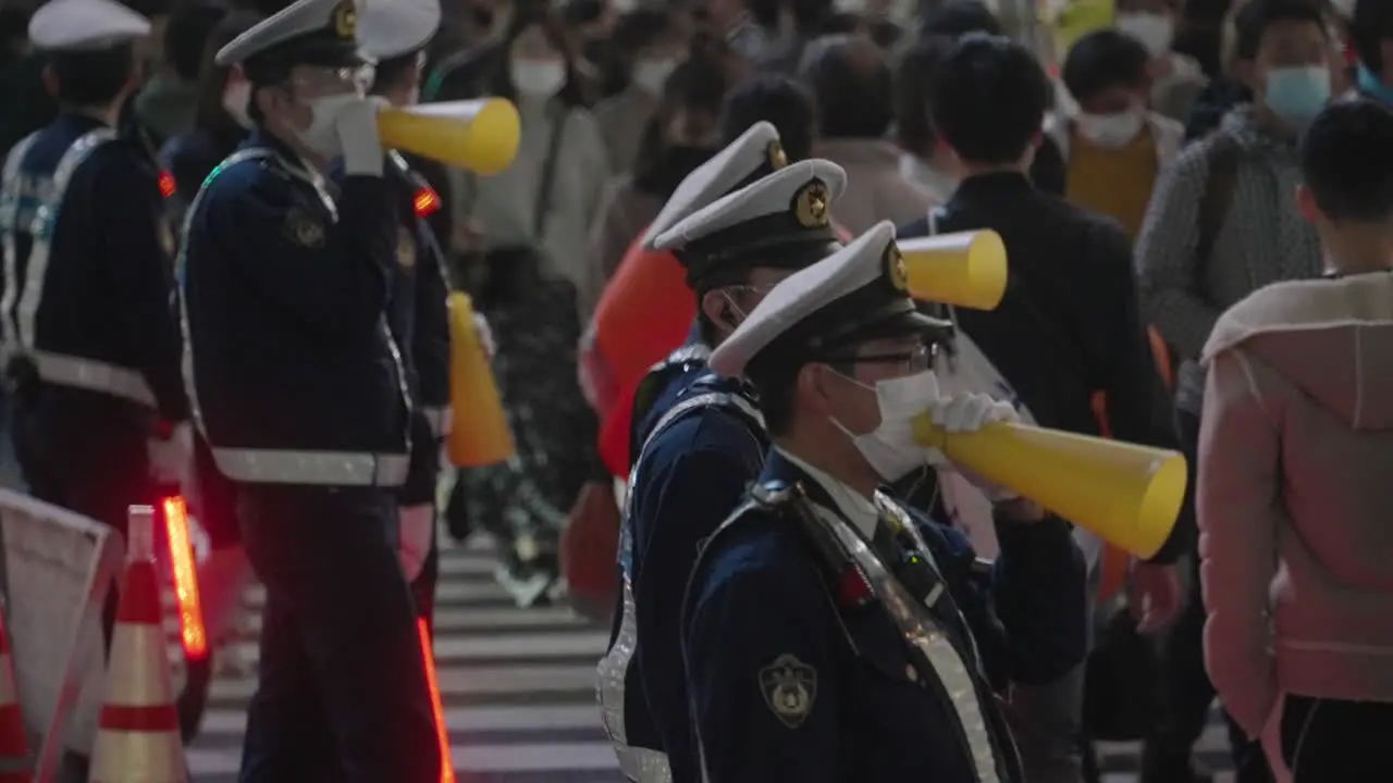 Group Of Cops Using Yellow Megaphones While Controlling The Crowd At Shibuya Crossing On Halloween Night 2020 Medium Shot