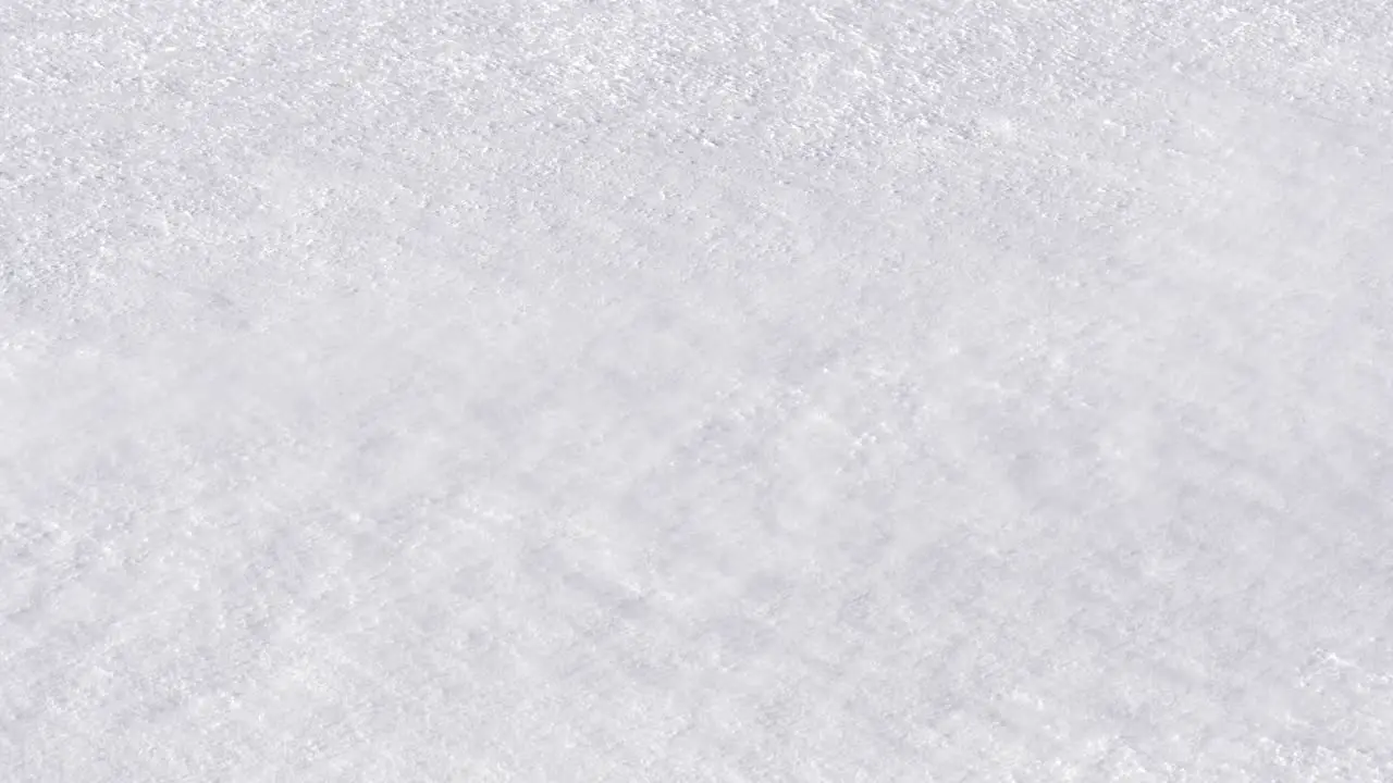 Cold breeze blowing swirls of powdery snow over frozen white ground Detail shot