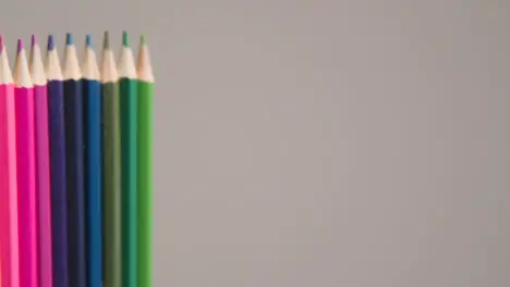 Studio Shot Of Rotating Line Of Multi-Coloured Pencils Against Grey Background 1