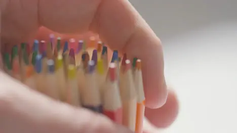 Close Up Of Person Picking Up And Dropping Multi-Coloured Pencils From Pot