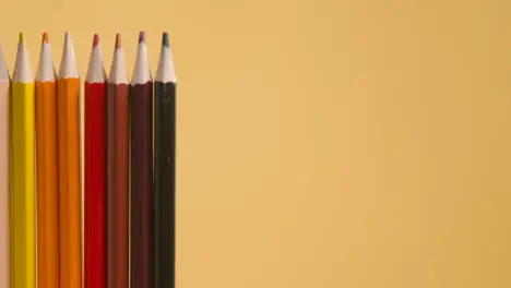 Studio Shot Of Rotating Line Of Multi-Coloured Pencils Against Yellow Background 3