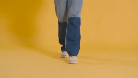 Close Up On Legs And Feet Of Woman Having Fun Dancing Against Yellow Studio Background 1