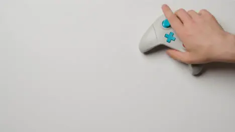 Overhead Studio Shot Of Hand Reaching In To Pick Up Video Game Controller 4