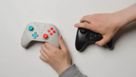 Overhead Studio Shot Of Hands Reaching In To Pick Up Video Game Controllers