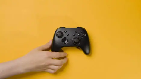 Overhead Studio Shot Of Hand Reaching In To Pick Up Video Game Controller 5