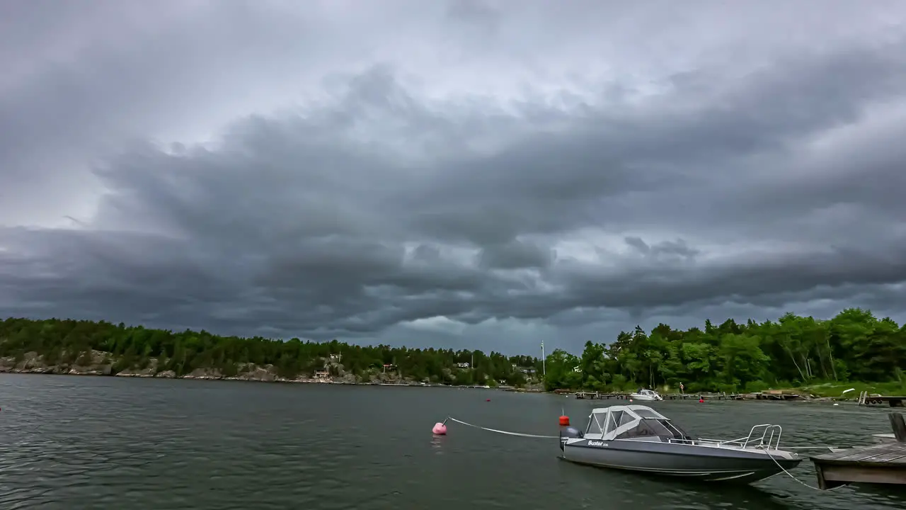 A boat docked at a lake in Sweden with a dark ominous cloudscape overhead time lapse