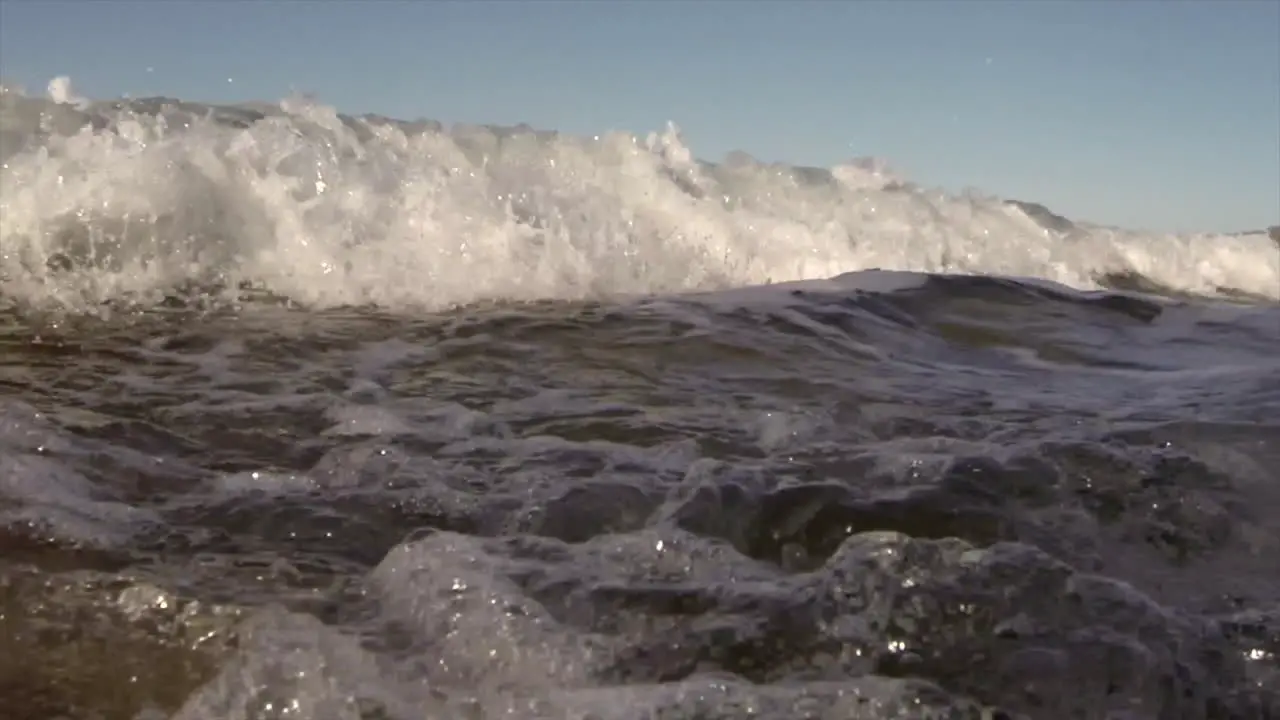 Water level view of waves crashing and rolling into shore in slow motion 7