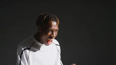 Portrait Of Young Male Footballer Wearing Club Kit In Studio Celebrating Goal 