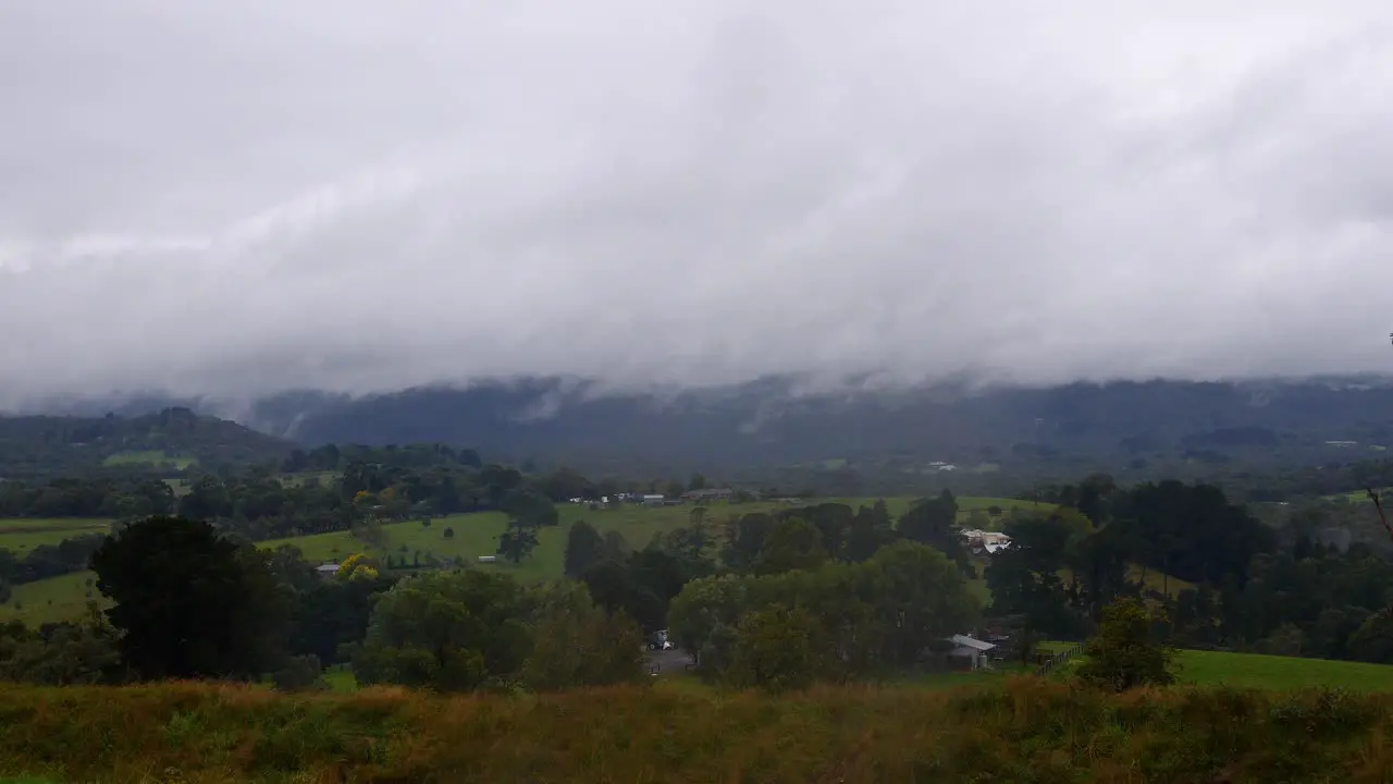 A slow time lapse of misty rainy white clouds rolling across a rural landscape in Australia during the winter