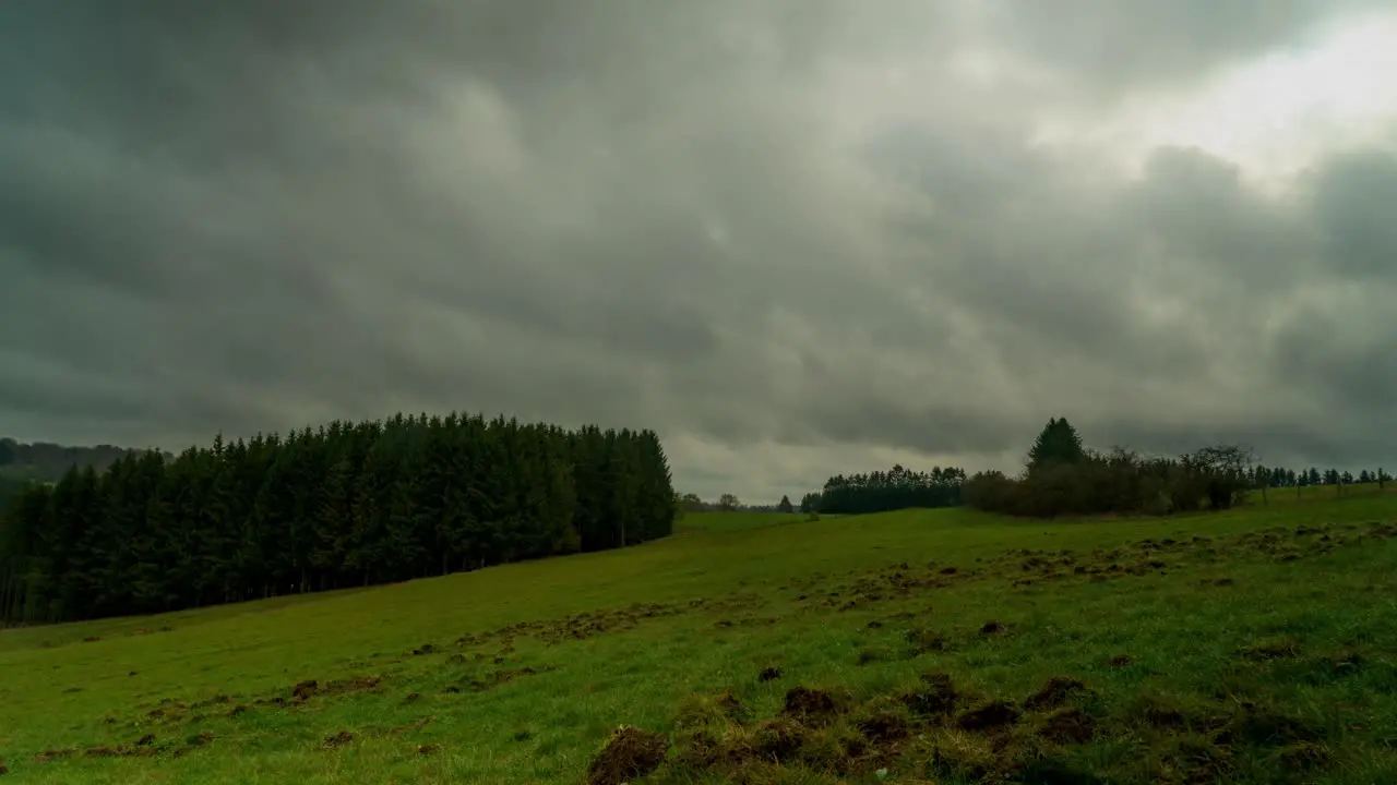 Timelapse of clouds fly above vibrant green meadow in rural landscape