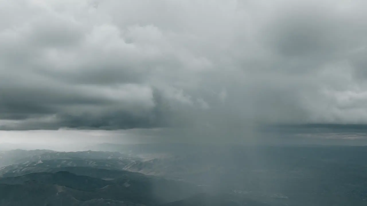 Storm clouds shower rain down over mountain range