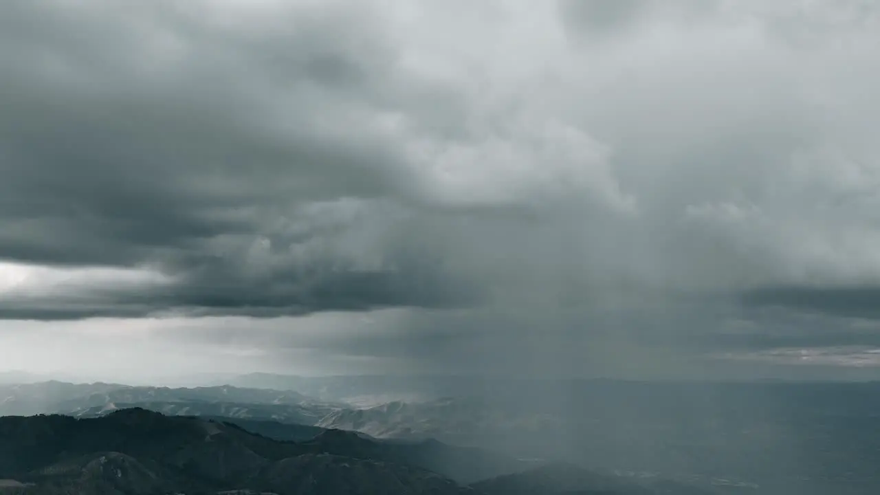 Aerial of storm clouds raining down on mountain range