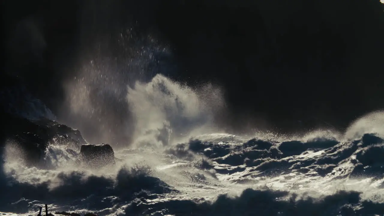 Ocean waves roll into a rocky shore in slow motion