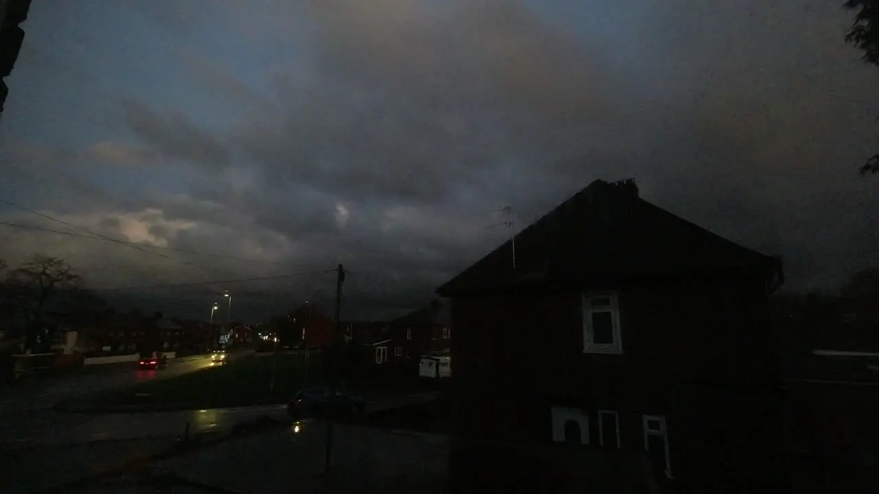 Gloomy evening storm clouds and vehicle headlights passing across British town house time lapse