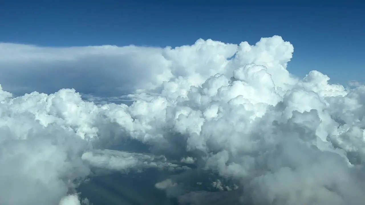 Aerial view taken from a cockpit of some huge white cumuloninbus during daylight at cruise level