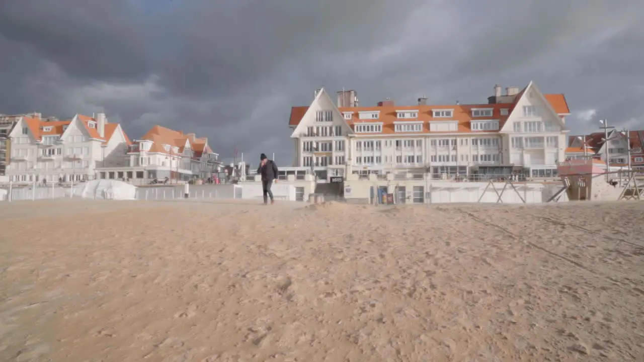 Senior man walking on the beach of coastal village De Haan in Belgium during windy autumn day