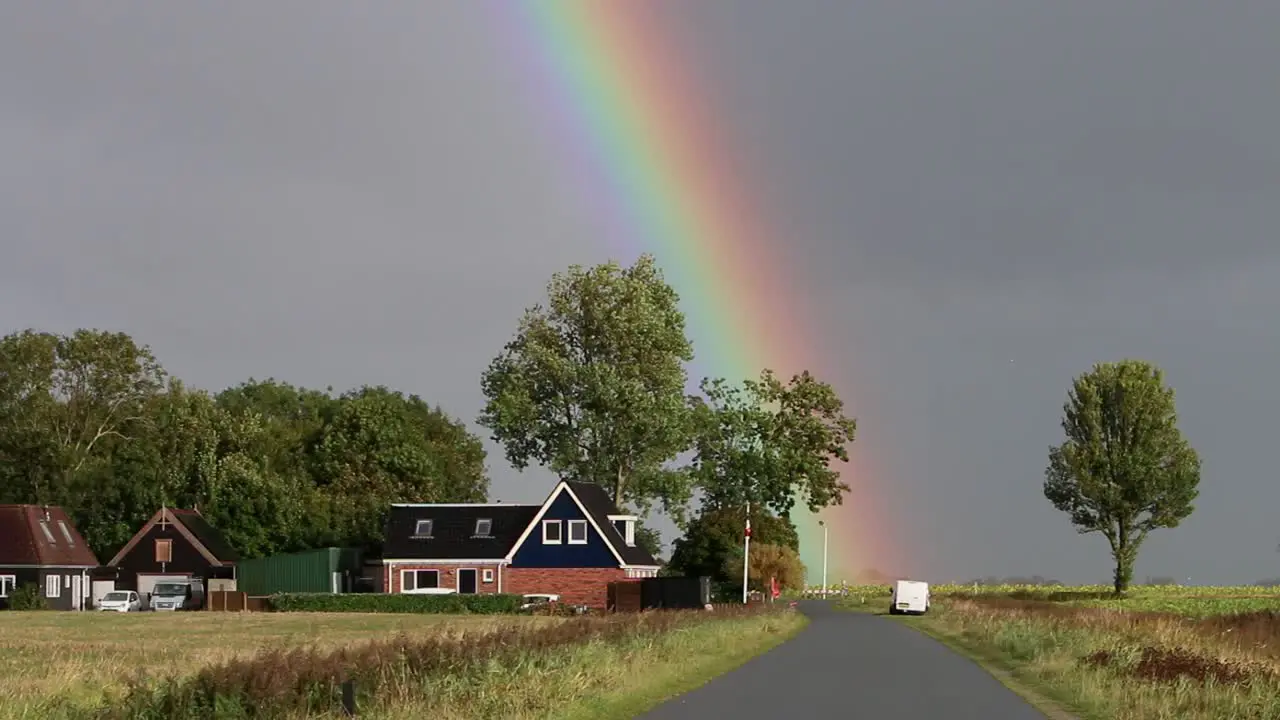 Rainbow and stormy sky over house and road