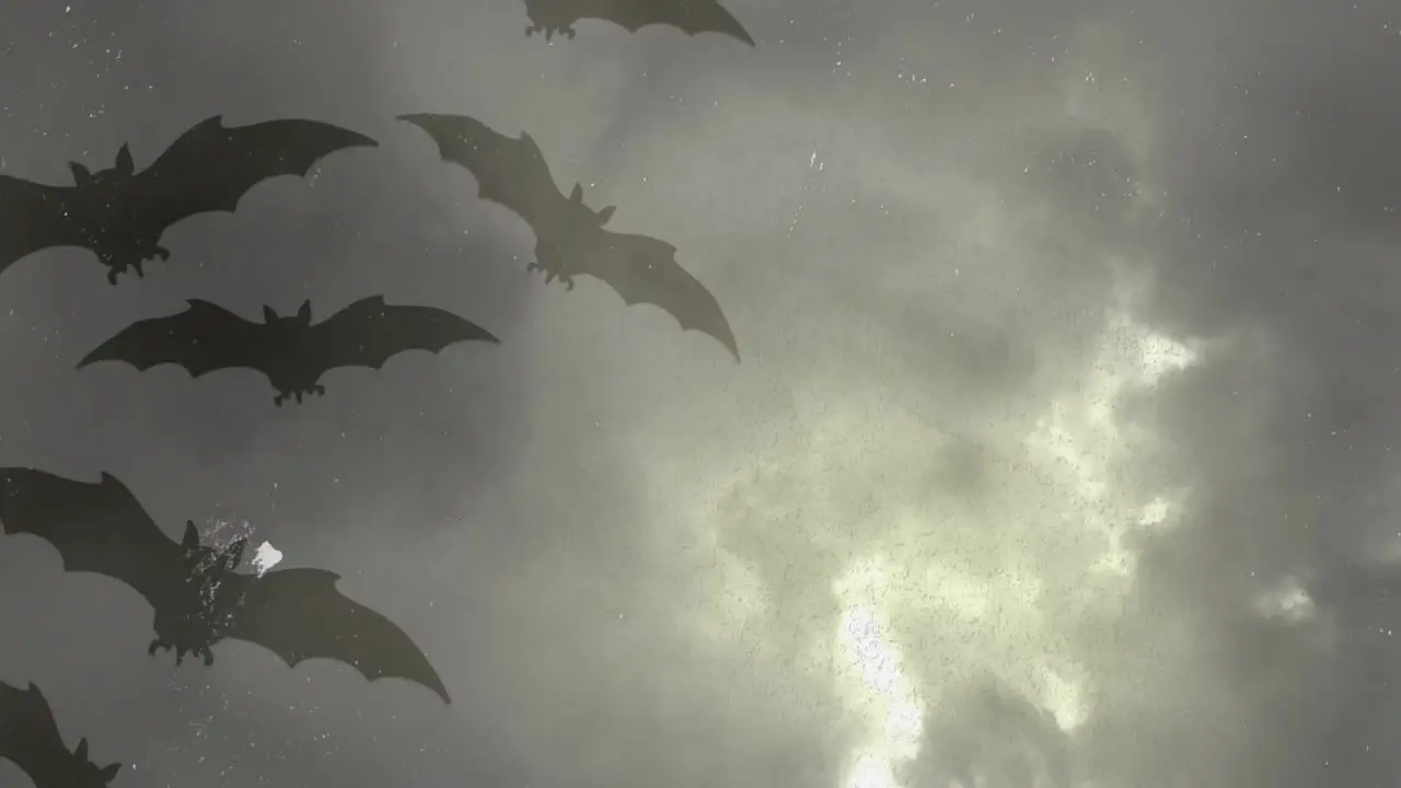 Animation of halloween grey bats over grey stormy sky with lightnings in background