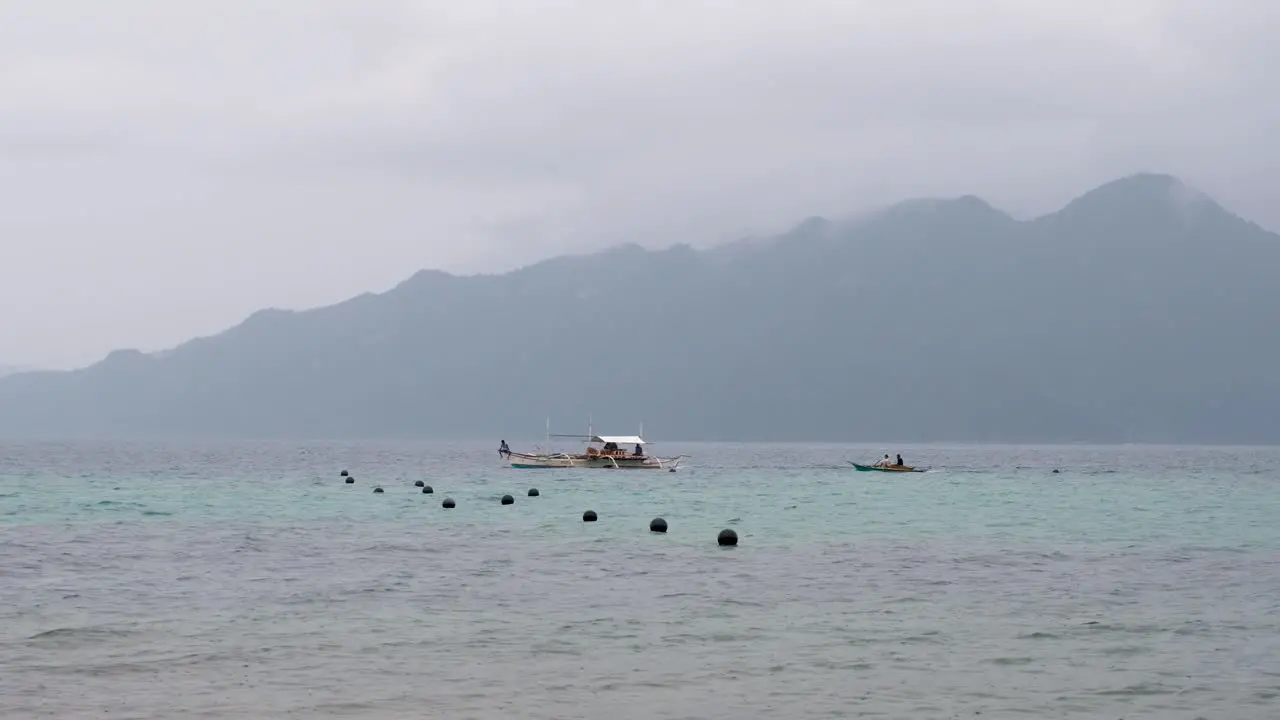 Local fishing and transport boats traveling in Coron Bay with remote tropical island in the distance Palawan Philippines Southeast Asia