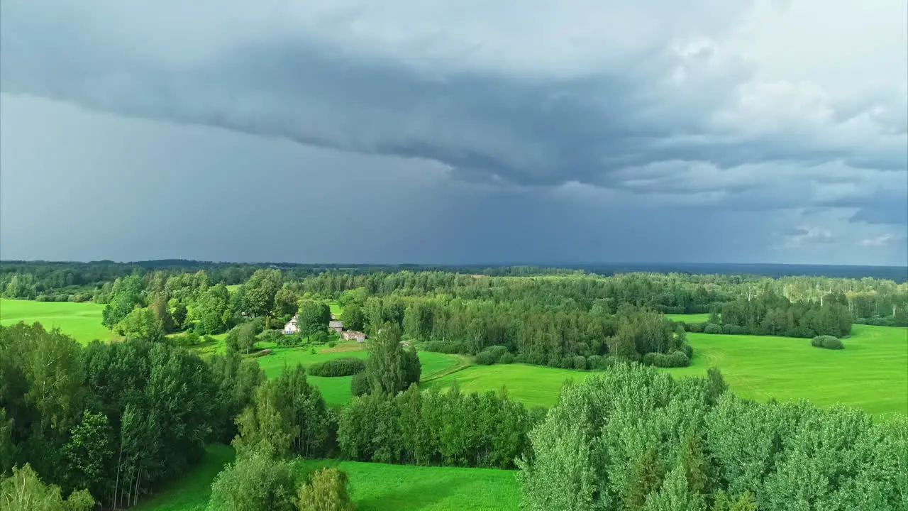 Aerial view of forests with green grasslands under dark rain clouds