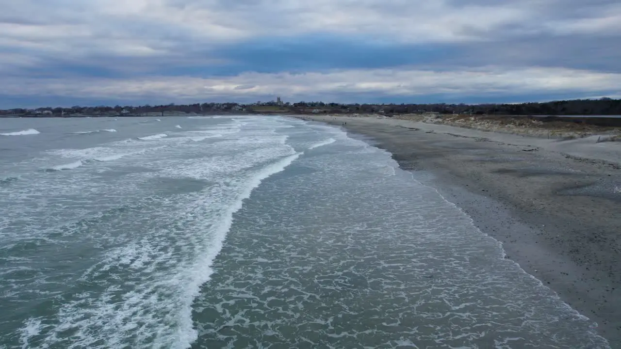 Aerial of ocean waves crashing on a beach on a cloudy day