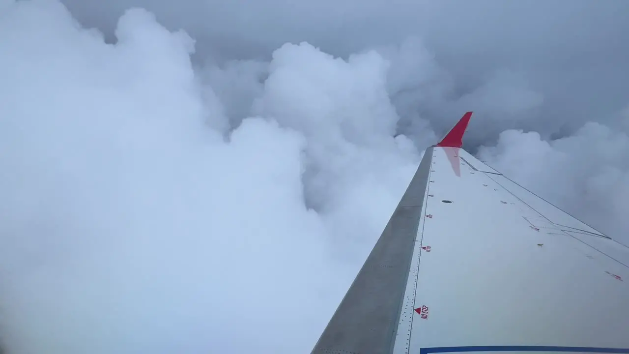 Right wing of a jet flying trough cumulus clouds