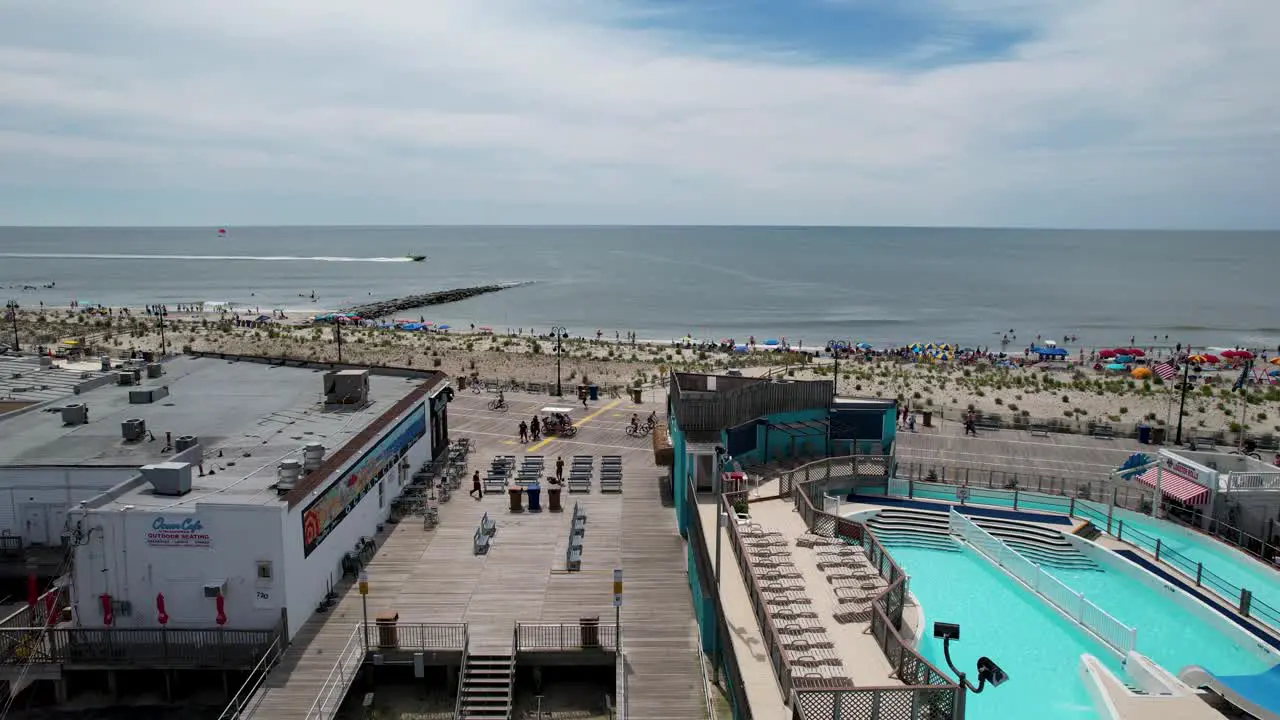 Aerial drone shot showing a busy boardwalk and a crowded beach on a summer day at the Jersey Shore