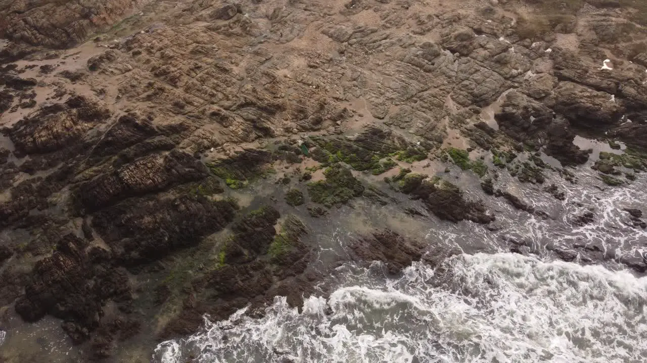 aerial view of a surfer on the rocks on the coast at punta del este in uruguay