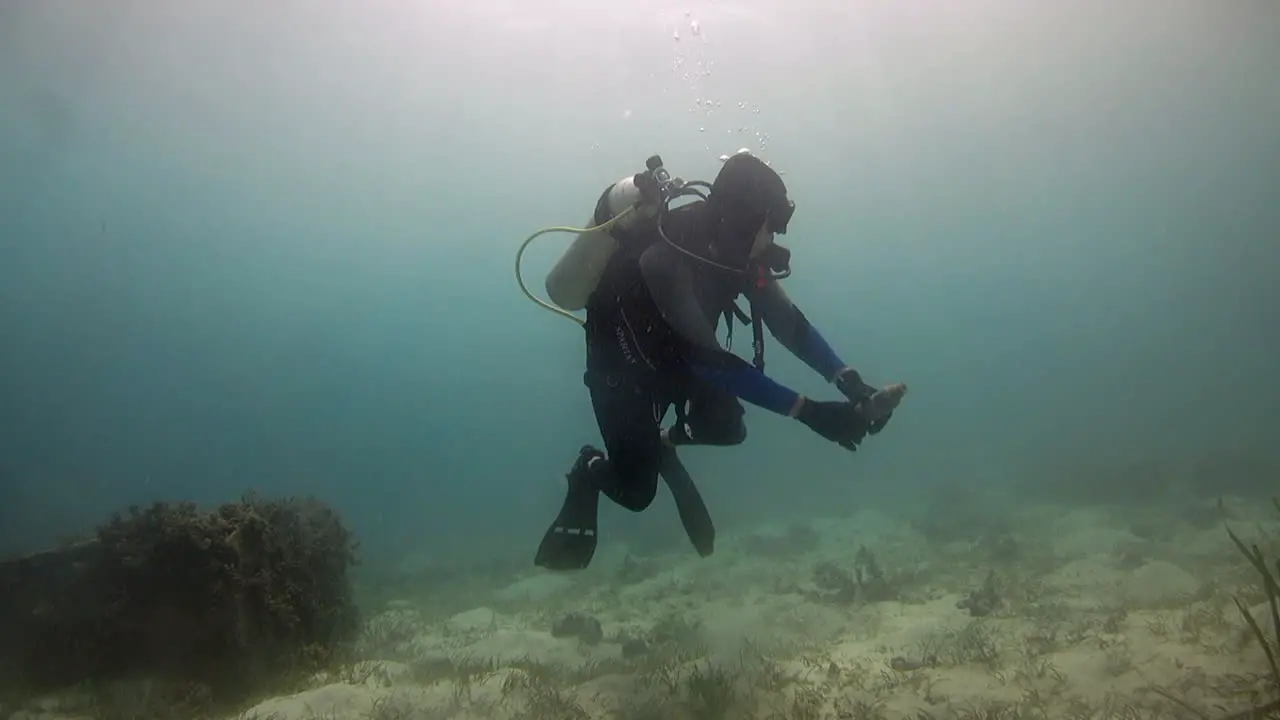 Scuba diver picking up plastic bottle from ocean floor